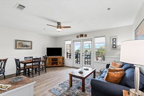 A living room with a television, dining table, chairs, and a sofa. - Cozy Family condo with Gulf views and easy Beach Access (Destin)
