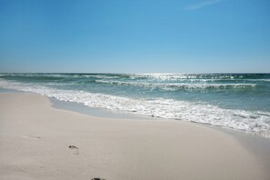 Uma praia com céu claro e ondas do oceano.