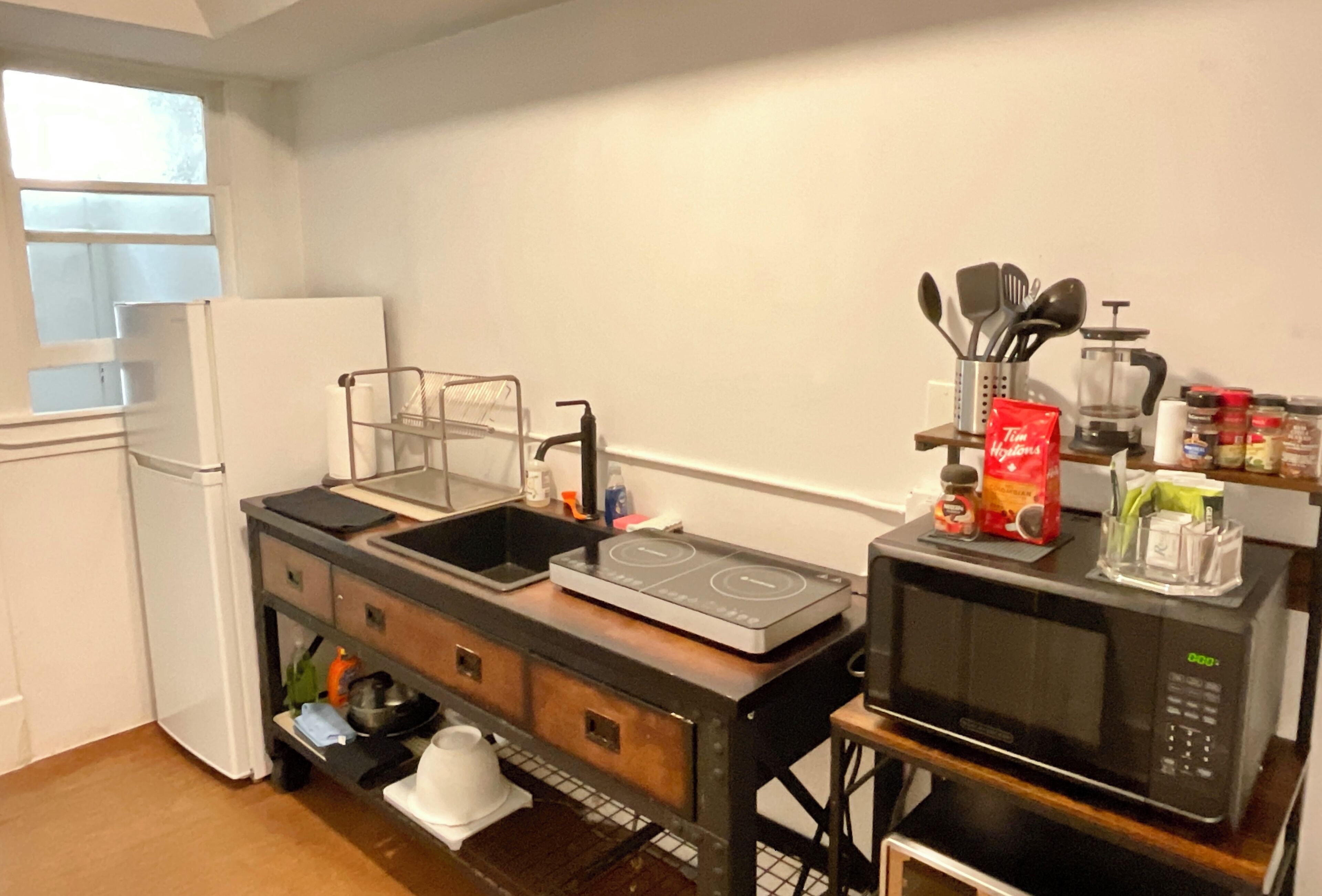 A compact kitchen with a sink, stove, microwave, and a refrigerator.