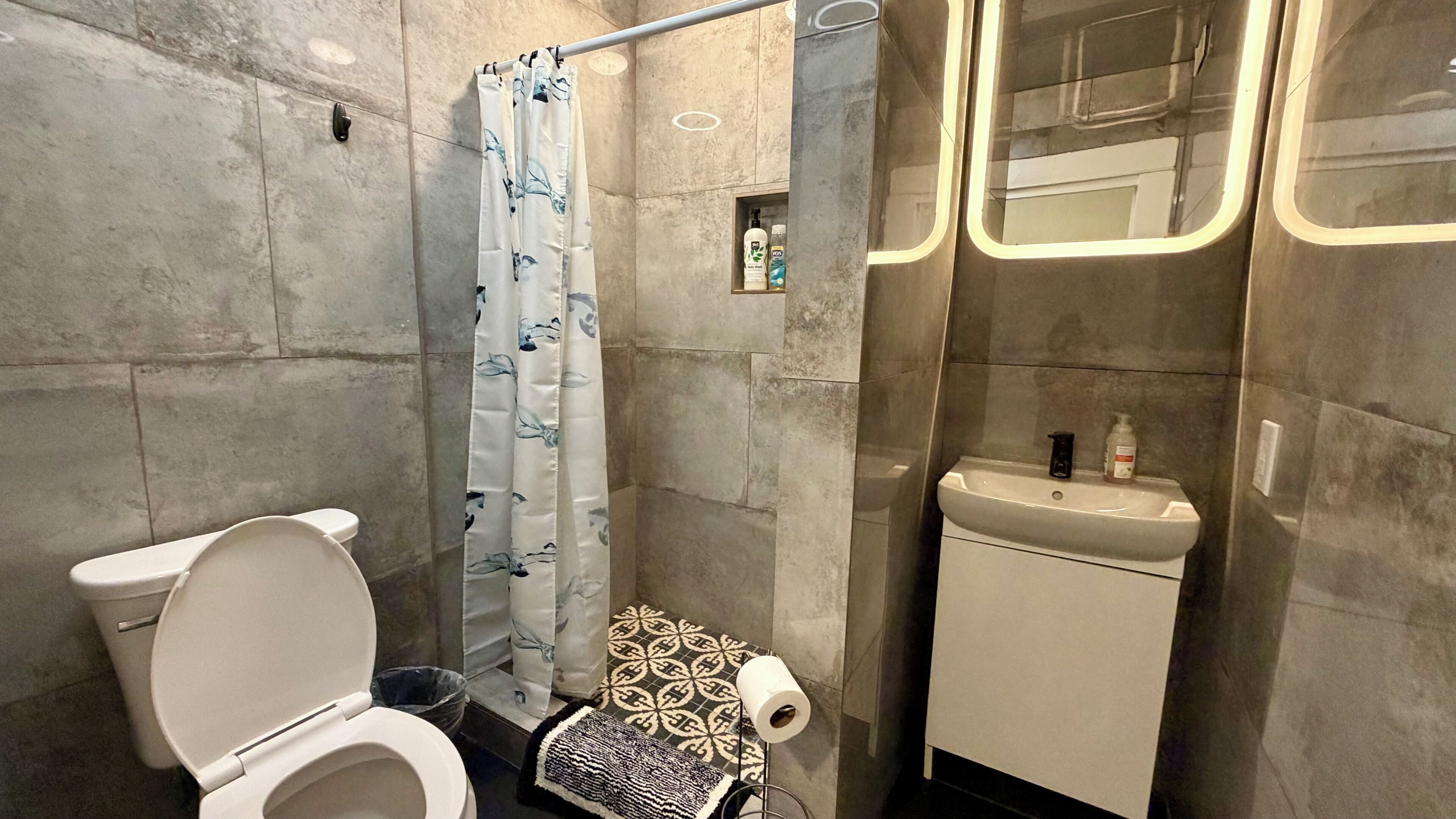 Une salle de bain moderne équipée de toilettes, d’une douche et d’un lavabo.