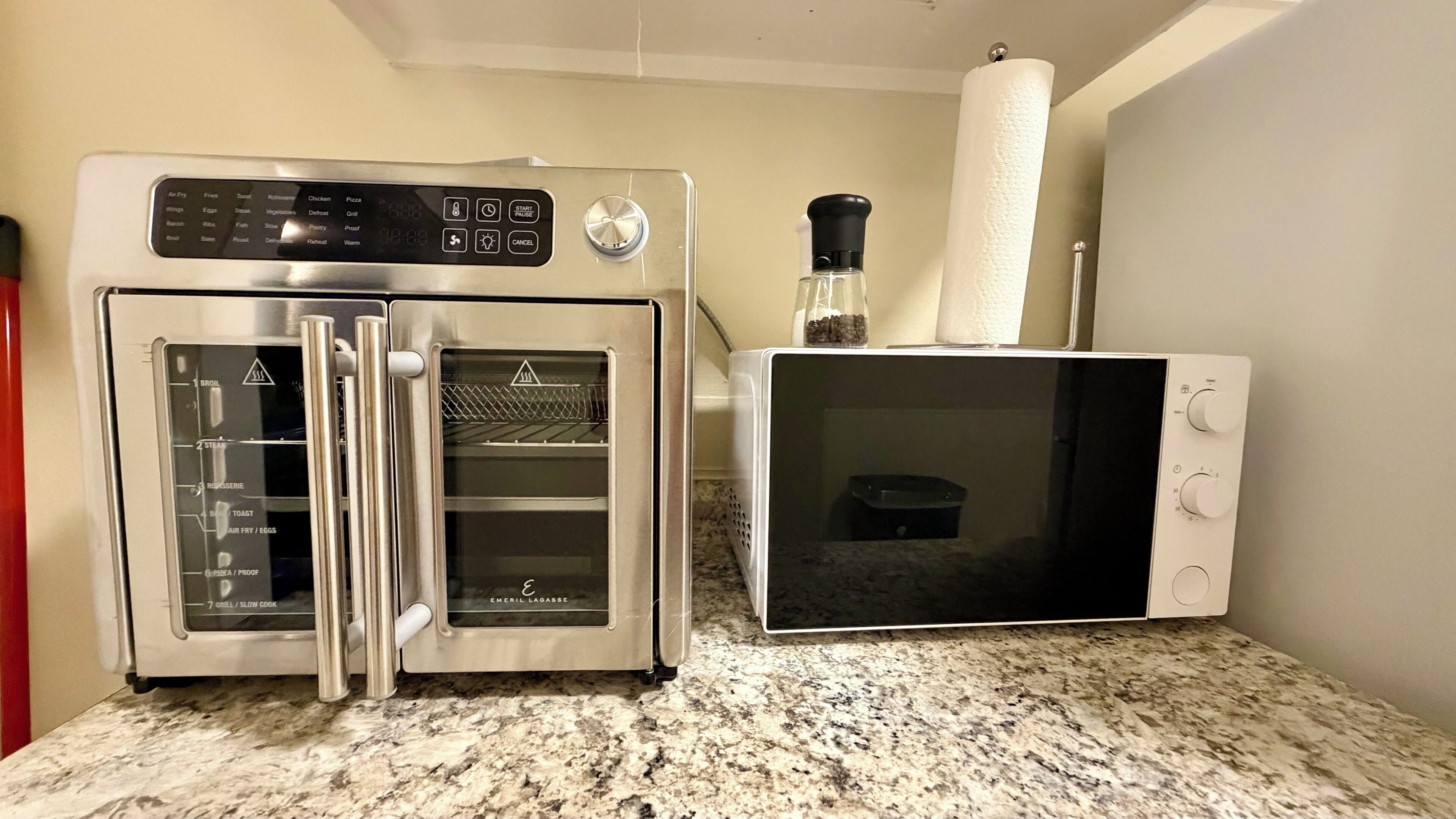 A kitchen with a stainless steel oven, a microwave, and a paper towel dispenser.