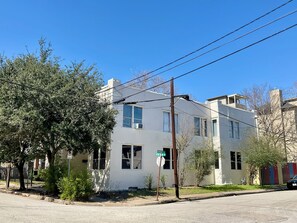 A two-story building with a white exterior, multiple windows, and a street sign indicating 'MORGAN AVE' and 'HYDE PARK'. - The Huntington in the Heart of Montrose (Houston)