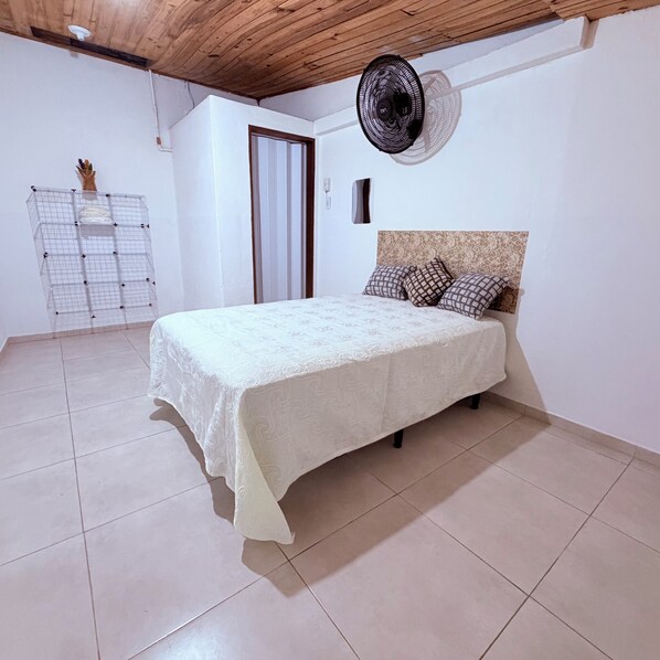 A bedroom with a bed, a ceiling fan, and a window.