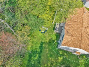 An aerial view of a backyard with a circular seating arrangement, a wooden deck, and surrounding greenery. - Spacious Poconos Retreat for Families & Groups (Tobyhanna)