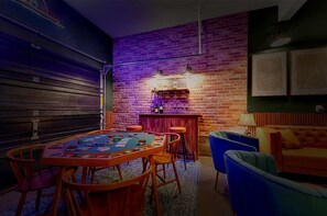A cozy room with a brick wall, a wooden table with chairs, a bar area, and a blue armchair. - Spacious Poconos Retreat for Families & Groups (Tobyhanna)