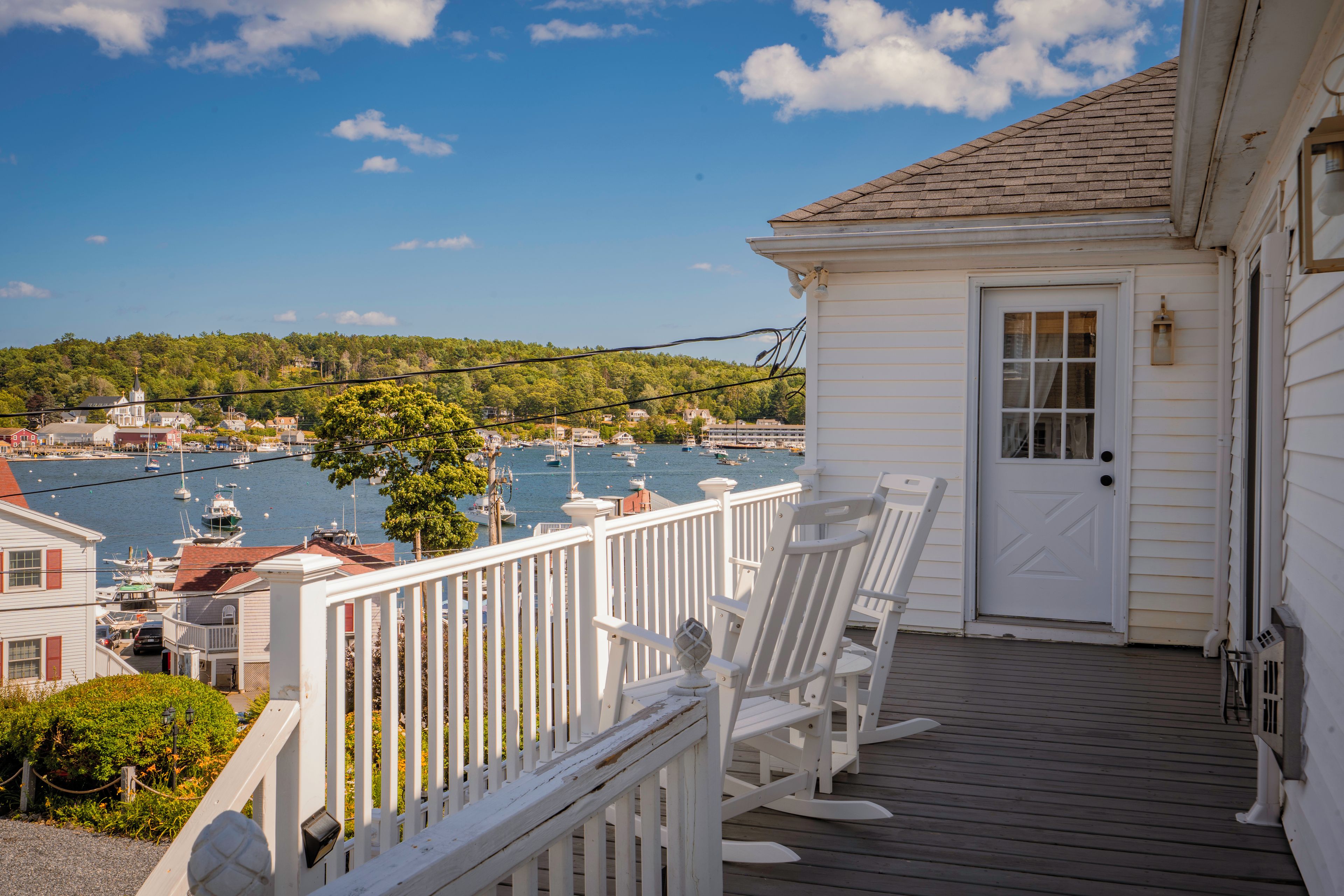 A wooden deck with white railings overlooking a marina with boats.