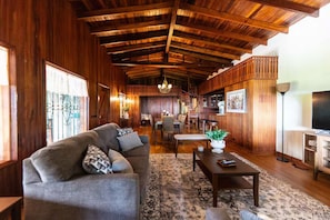 A cozy living room with a wooden ceiling, a sofa, a coffee table, and a TV.