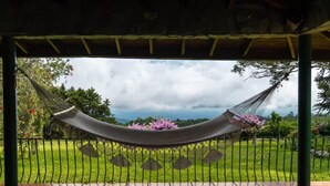 Un'amaca sotto una pergola con vista su un giardino e un paesaggio lontano.