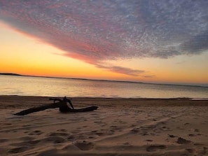 A beach with footprints leading to a boat.