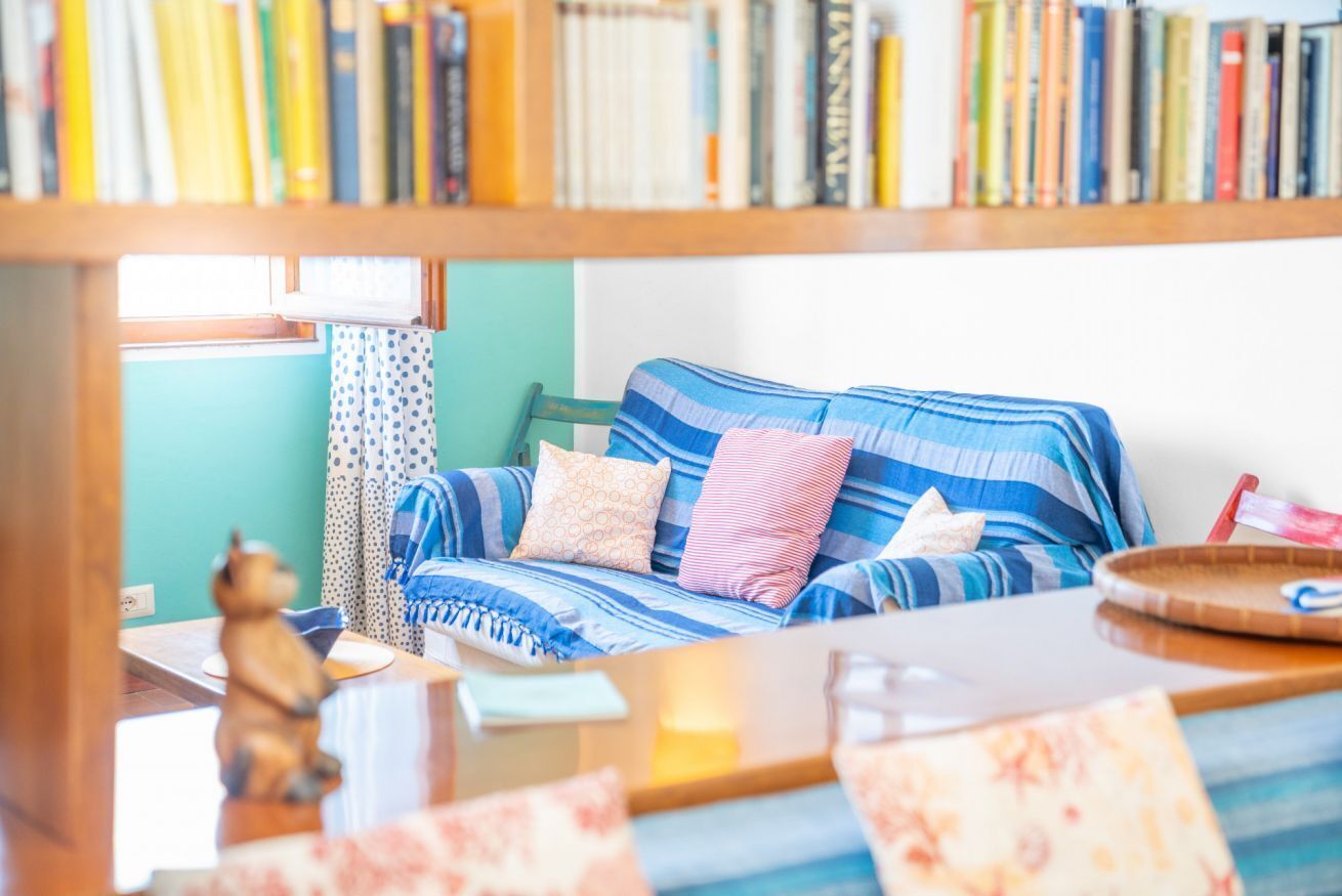 A cozy room with a striped sofa, a small table, and a bookshelf filled with books.