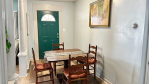 A dining area with a wooden table and chairs, a green door, and a painting on the wall. - 3 Queen Beds*Near BU & Hospitals*Crews Welcome (Johnson City)