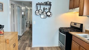 A kitchen with a stove, oven, and a pot rack with various pots and pans. - 3 Queen Beds*Near BU & Hospitals*Crews Welcome (Johnson City)
