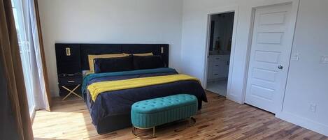 Un dormitorio con cama, una banca, ventilador de techo y suelo de madera.