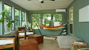 A room with large windows, a hammock, wooden furniture, and a ceiling fan. - Cozy 3-Bedroom House in Quaint Douglasville (Douglasville)