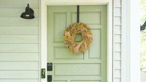 A light green door with a wreath, a doormat, and a small porch with a white railing. - Cozy 3-Bedroom House in Quaint Douglasville (Douglasville)