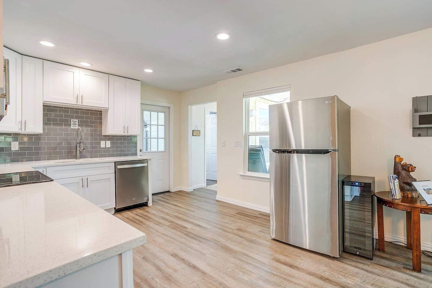 A modern kitchen with white cabinets, a stainless steel refrigerator, and a dishwasher.