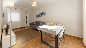 Una sala moderna con una mesa de comedor, sofá y televisor de pantalla plana.