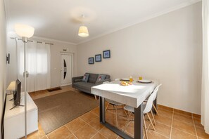 A modern living room with a dining table, sofa, and a flat-screen TV. - Ferrel Dreams - Coastal Break (Peniche)