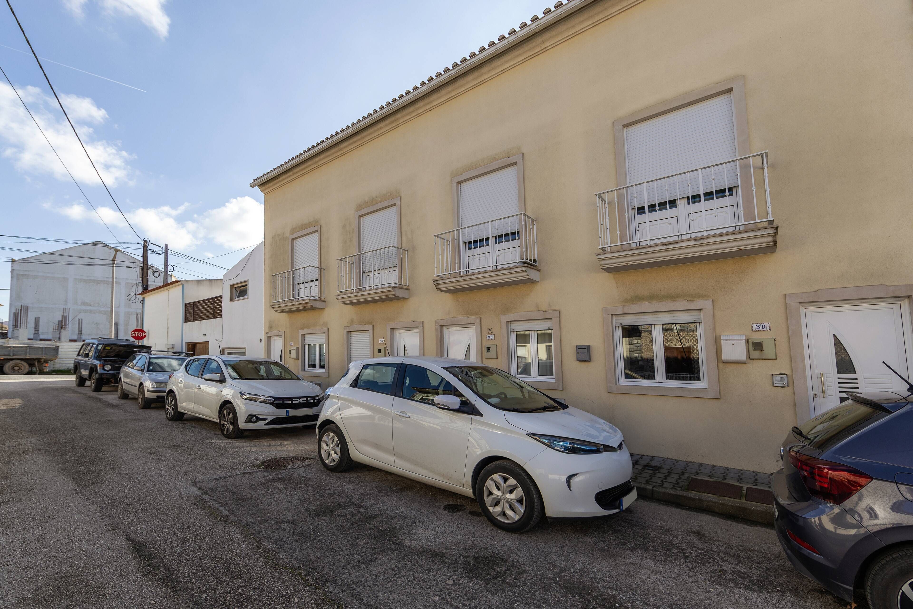 A row of parked cars in front of a building with multiple windows and balconies.