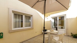 Un patio con mesa y sillas, una ventana y una puerta.