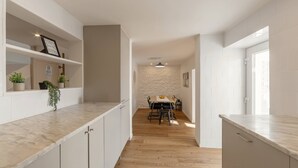 Una cucina moderna con mobili bianchi, un piano di lavoro in marmo e un'area pranzo con tavolo e sedie.