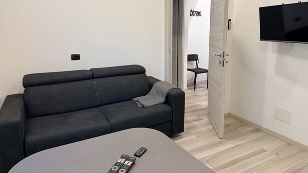 Una sala de estar moderna con un sofá gris, un sillón gris y un televisor de pantalla plana montado en la pared.