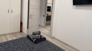 Un pasillo con un armario, una puerta, un televisor montado en la pared y una alfombra estampada.