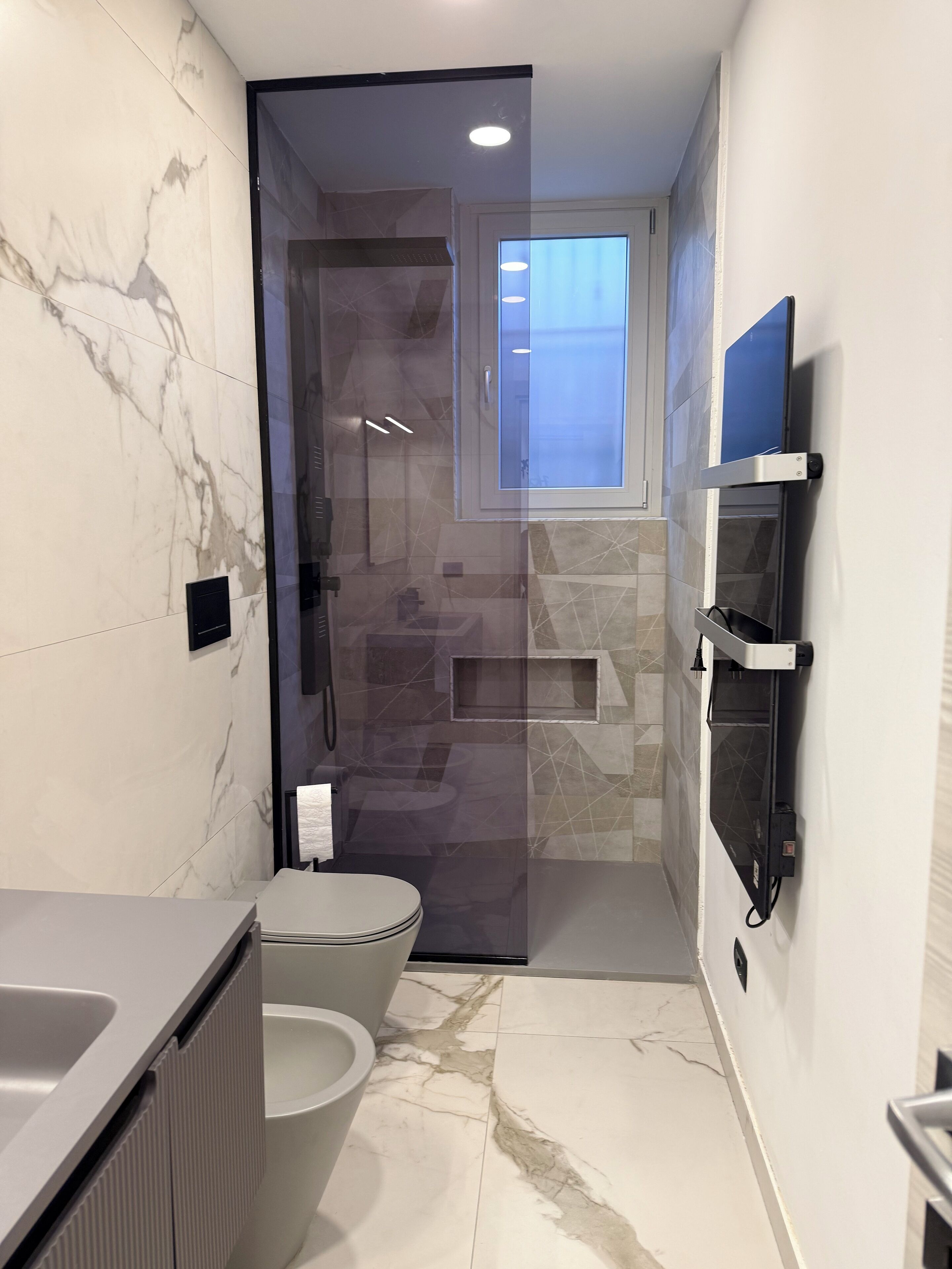 Une salle de bain moderne équipée de toilettes, d’une douche et d’étagères intégrées.