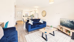 Un salon moderne avec un canapé bleu, une table basse et un téléviseur.