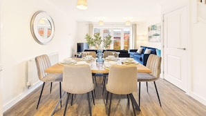 Un coin repas avec une table en bois, quatre chaises et un vase avec des plantes.