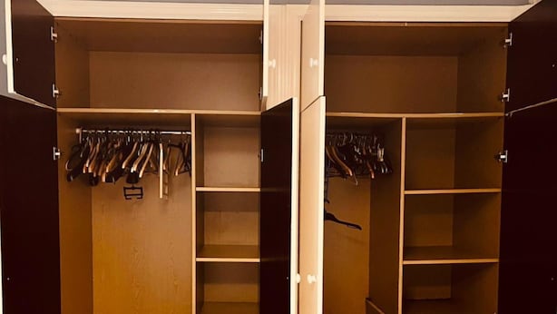 Un dressing avec de nombreuses étagères et un espace pour suspendre les vêtements, comprenant une section avec un miroir et un petit meuble de rangement.