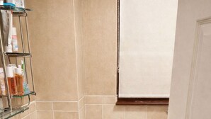 Une salle de bain avec des carreaux de couleur beige, un lavabo blanc et trois poubelles alignées contre le mur.