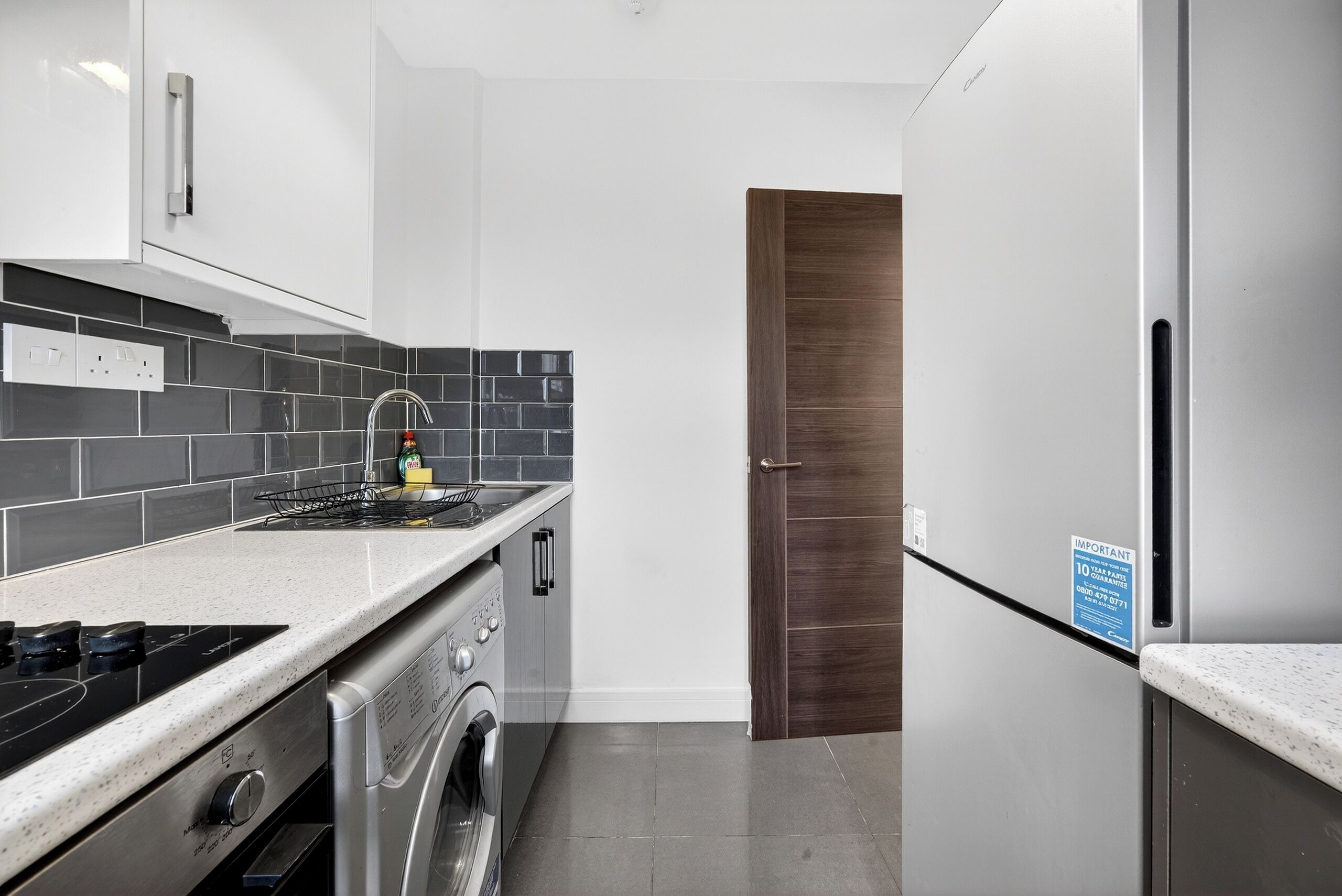 Una cocina moderna con un refrigerador de acero inoxidable, un horno empotrado y una lavadora.