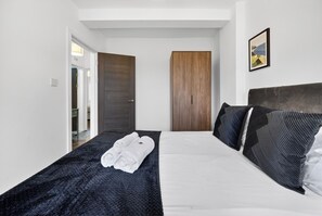 A hotel room with a bed, a wooden door, and a framed picture on the wall. - Amber Vista Apartments Cardiff (Cardiff)