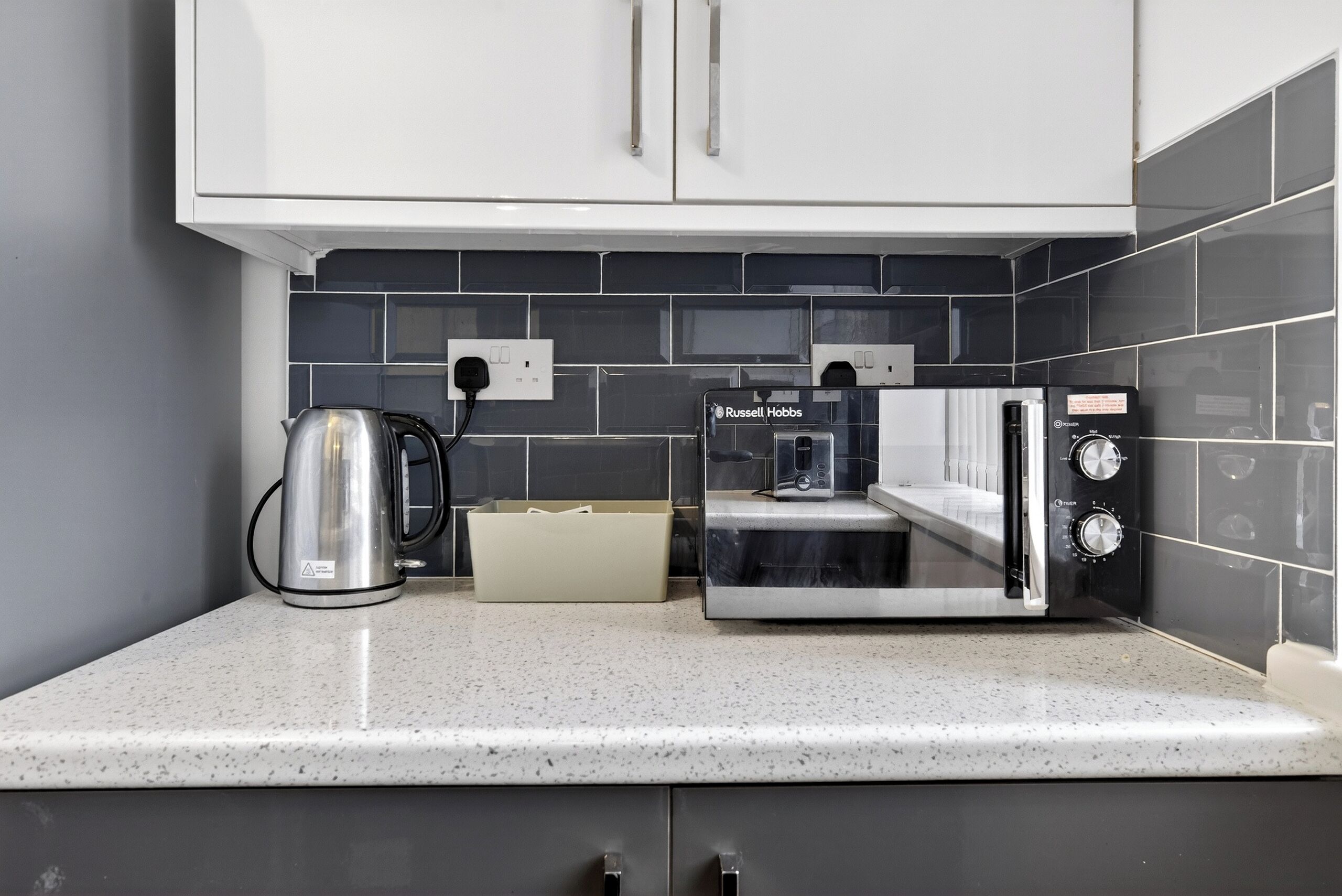 A kitchen with a kettle, a coffee machine, and a toaster on the counter.