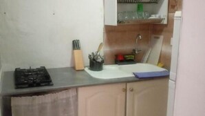 Une cuisine de taille réduite, équipée d’une cuisinière à gaz, d’un évier et d’un plan de travail.