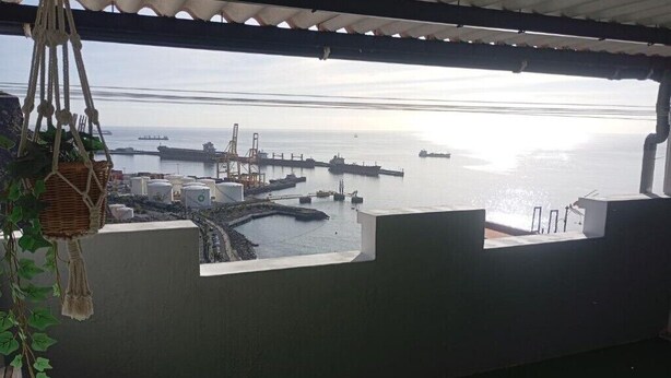 Une vue depuis un balcon donnant sur un port, avec des navires et des installations industrielles.