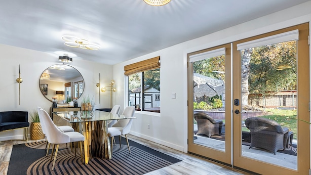 Un espace repas moderne avec une table en verre, des chaises blanches et un grand miroir.