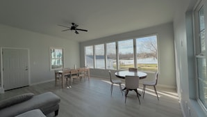 Un salón espacioso con zona de comedor, ventanas amplias y ventilador de techo.