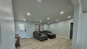 Un salón amplio con un sofá modular, una mesita y una puerta con un vitral.