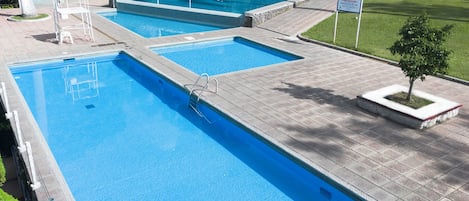 Una piscina con dos áreas diferenciadas, una escalera y un cartel.