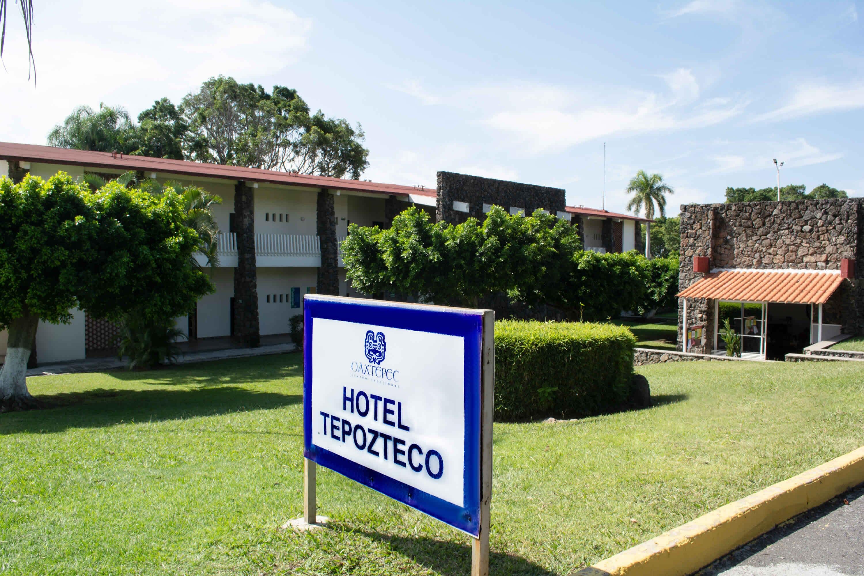 A sign for Hotel Tepozteco with a clear view of the building's exterior, including a red-tiled roof and a stone facade.