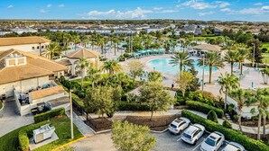 A resort with a swimming pool, palm trees, and a parking area.