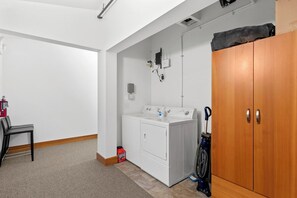 A laundry room with a washing machine, a dryer, a wooden wardrobe, and a vacuum cleaner. - As the sun sets over Leavenworth, the gas fireplace at Klonaqua casts a warm glo (Leavenworth)