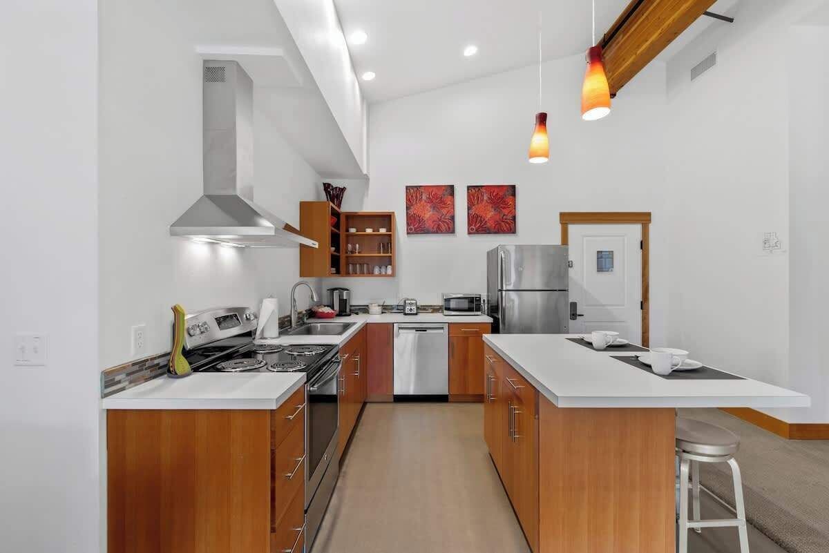Una cocina moderna con armarios de madera, electrodomésticos de acero inoxidable y una isla central.