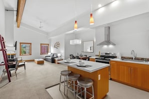 A modern kitchen with a central island, bar stools, and a dining area with a sofa and chairs. - As the sun sets over Leavenworth, the gas fireplace at Klonaqua casts a warm glo (Leavenworth)