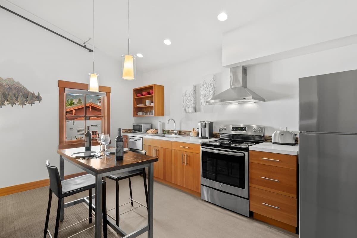 Una cucina moderna con elettrodomestici in acciaio inossidabile, mobili in legno e una zona pranzo con tavolo e sedie.