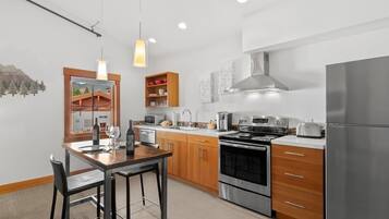 Una cucina moderna con elettrodomestici in acciaio inossidabile, mobili in legno e una zona pranzo con tavolo e sedie.