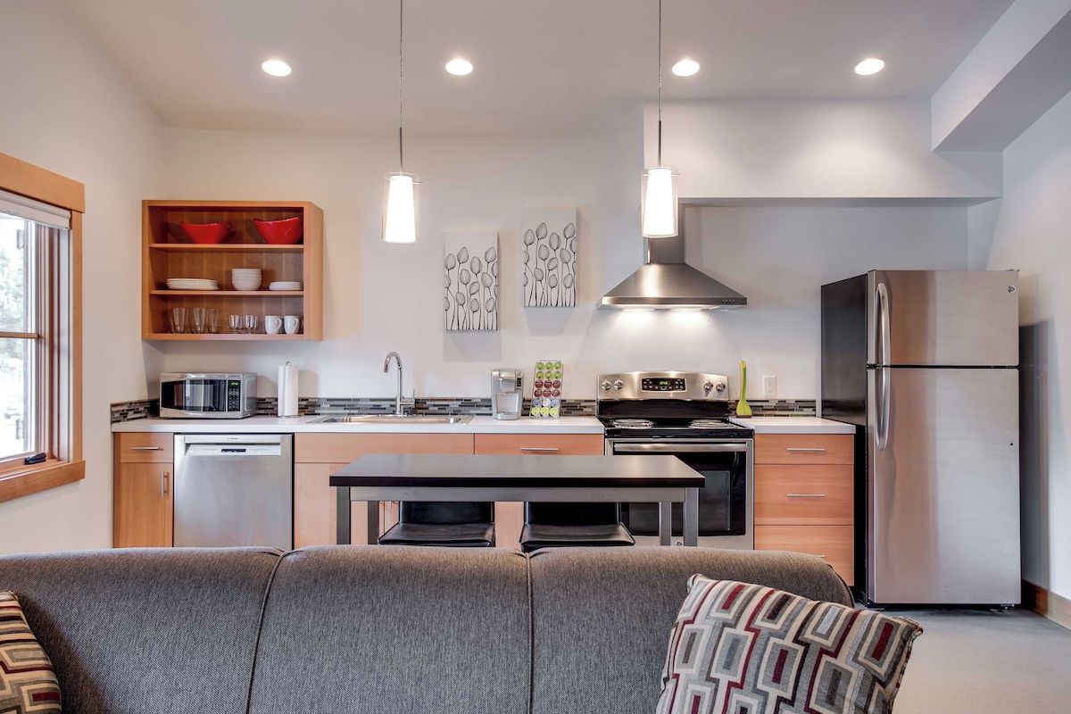 A modern kitchen with a dining area, stainless steel appliances, and pendant lighting.