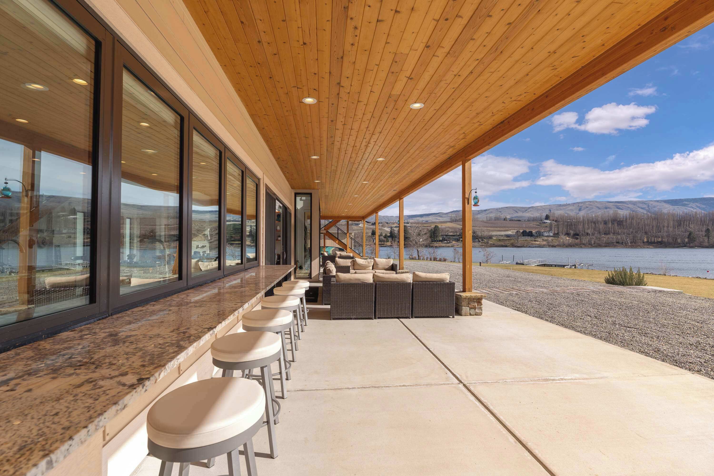 A covered outdoor seating area with a view of a lake and mountains.
